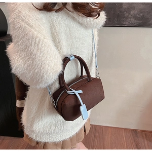 Close-up of brown suede pillow bag with light blue straps and stylish metal hardware