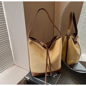 Detail of khaki canvas tote bag with dark brown leather trim and drawstring detail