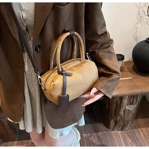 Detailed close-up of dark khaki suede Boston bag with leather tag and shoulder strap