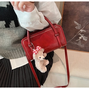 Detail of dark red vintage leather box bag with adjustable strap and bear pendant