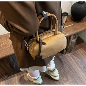 Detail of suede boston bag with top handles, metal zipper and detachable chain strap