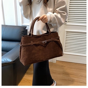 Gros plan d'un sac cabas en daim marron avec boucle argentée et texture douce