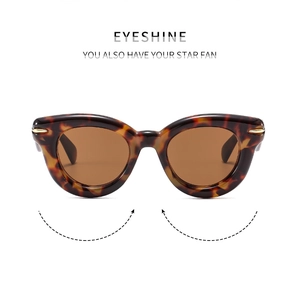 Detailed close-up of tortoiseshell cat-eye sunglasses with gold arrow metal hinge accents