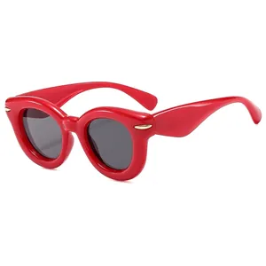 Fashionable red cat-eye sunglasses with gold rivets and dark lenses on white background