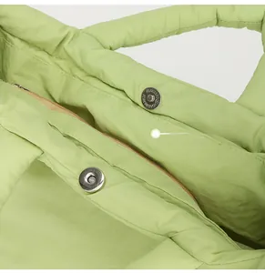 Close-up of dual metal magnetic buckles and zipper closure on a quilted nylon puffer bag