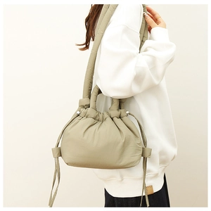 Detail of light olive quilted nylon shoulder bag with drawstring closure and padded strap