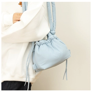 Detail of light blue quilted nylon shoulder bag with drawstring closure and soft texture