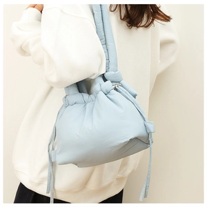 Close-up of quilted nylon crossbody cloud bag in light blue on a female model