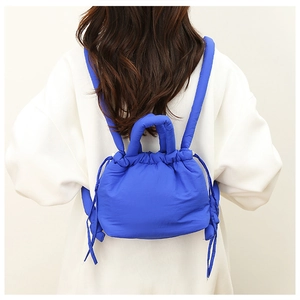 Detail of blue padded nylon drawstring bag shown on model's back for stylish look