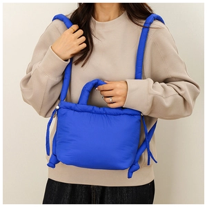 Detail shot of blue quilted puffer bag showing glossy nylon fabric and padded handle