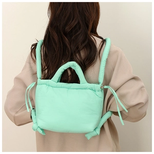 Rear view of mint green quilted puffy backpack with padded straps and soft texture