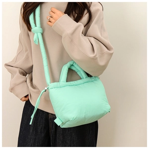 Detail of mint green quilted nylon handbag with adjustable strap and drawstring closure