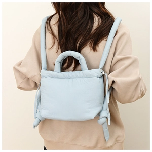 Detail view of light blue quilted nylon backpack showing adjustable straps and soft texture