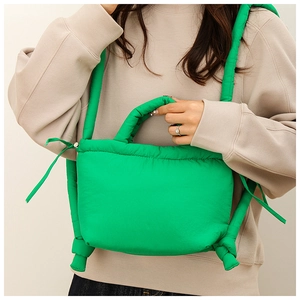 Close-up of bright green puffer shoulder bag with soft nylon fabric and knotted strap