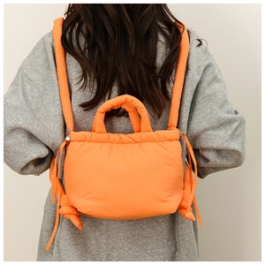 Quilted orange nylon tote bag detail with puffer texture and dual padded handles