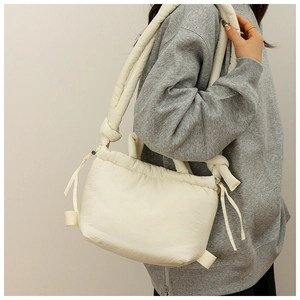 Model wearing a creamy white quilted nylon drawstring shoulder bag with a soft cloud texture