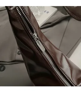 Detail of smooth silver metal zipper and fine stitching on dark brown leather handbag