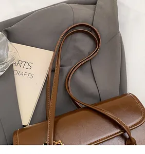 Close-up of brown vintage leather shoulder bag with smooth long straps and glossy texture