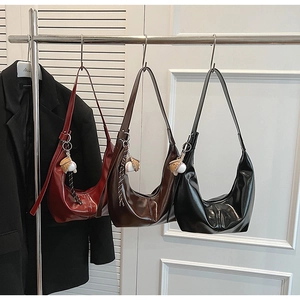 Detailed display of three shiny crescent shoulder bags with baseball charms in a shop
