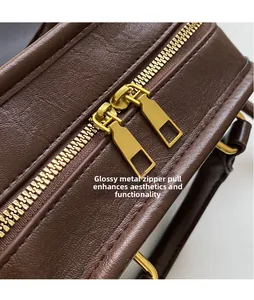 Close-up of dark brown lychee textured leather bag with smooth gold dual hardware zippers