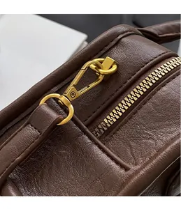 Macro shot of brown pebble leather bag featuring polished gold hardware and zipper