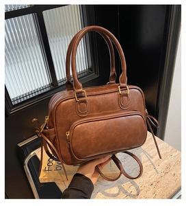 Detail view of vintage brown PU leather bag with gold hardware and tassel accent