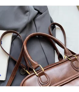 Detailed close-up of dark brown vintage leather bag with gold hardware and strap