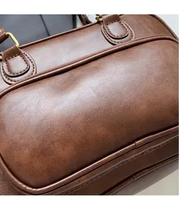 Close-up of brown textured leather backpack with gold metal rings and stitching