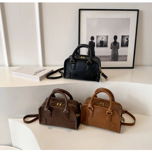Three vintage leather pillow bags in black and brown colors shown on minimalist display