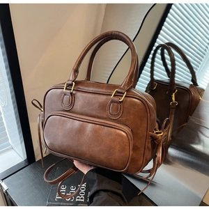 Close-up of vintage brown PU leather bag with brass hardware and front zipper pocket