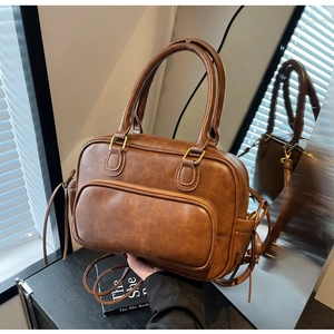 Detail of vintage brown leather Boston bag with golden hardware and front zip pocket