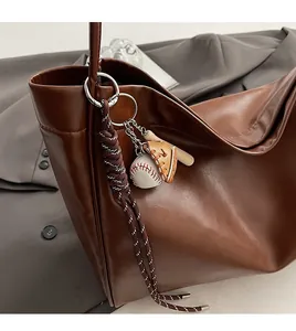 Detail of baseball charm with leather glove and wooden bat on a brown tote bag