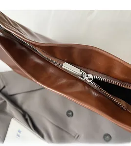 Close-up of smooth brown leather tote bag with durable silver metal zipper detail