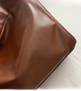 Close-up of matte dark brown leather texture and stitching detail on tote bag