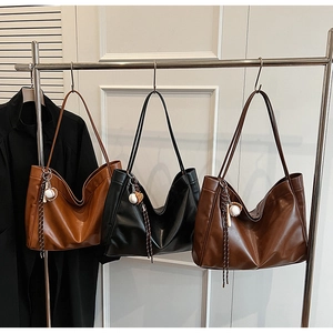 Detail view of large leather tote bags in brown and black with baseball charms