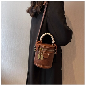 Détail du sac seau vintage avec foulard léopard sur la poignée et fermetures éclair dorées