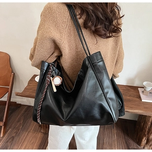 Detailed back view of a black large-capacity tote bag with unique baseball charm on model