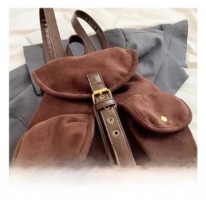 Close-up of vintage brown faux suede backpack featuring metallic snaps and buckle detail