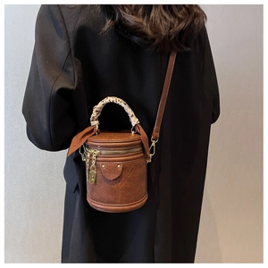 Brown cylinder bucket bag with leopard scarf handle and gold padlock detail worn by model