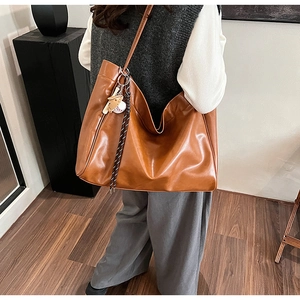 Detail shot of brown vintage tote bag with baseball charm and woven strap on model