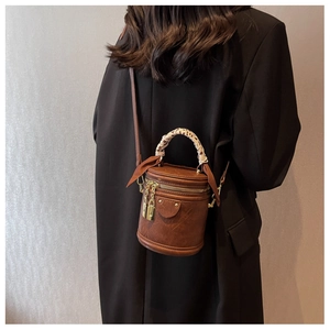 Sac seau cylindrique marron vintage avec foulard décoratif et zips dorés sur mannequin