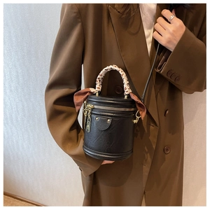 Détail d'un sac seau noir avec poignée en foulard sur une femme en blazer marron