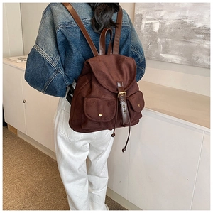 Detail of dark brown faux suede backpack with flap cover and leather buckle straps