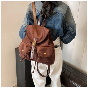 Detail eines braunen Vintage-Wildlederrucksacks mit doppelten Fronttaschen und Kordelzug