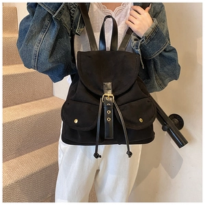 Detail eines schwarzen Wildleder-Rucksacks mit Goldnieten, Metallschnallen und Kordelzug