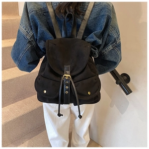 Detailansicht eines schwarzen Wildleder-Rucksacks mit Vintage-Lederriemen am Modell