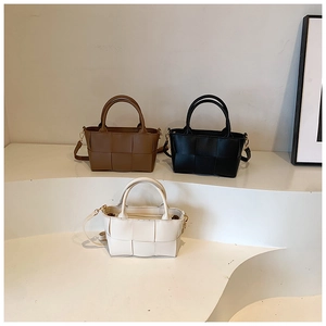 Detail view of woven leather texture on small square handbags in three classic colors