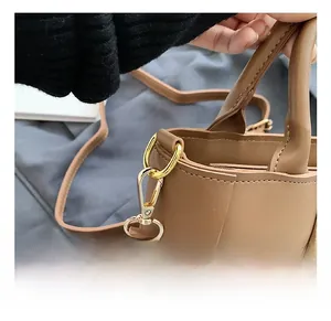Close-up of golden metal hooks and woven texture detail on the brown crossbody handbag