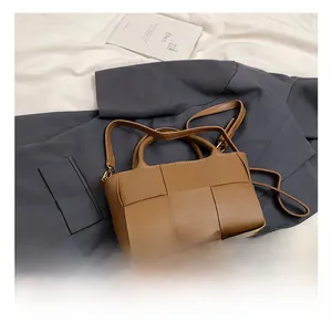 Detailed view of brown woven leather handbag with matching handle and shoulder strap