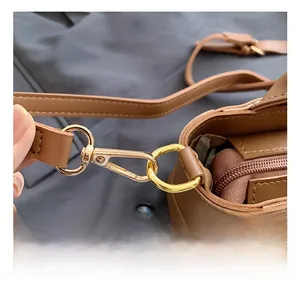 Macro detail of high-quality light gold metal hook and strap connection on brown crossbody bag